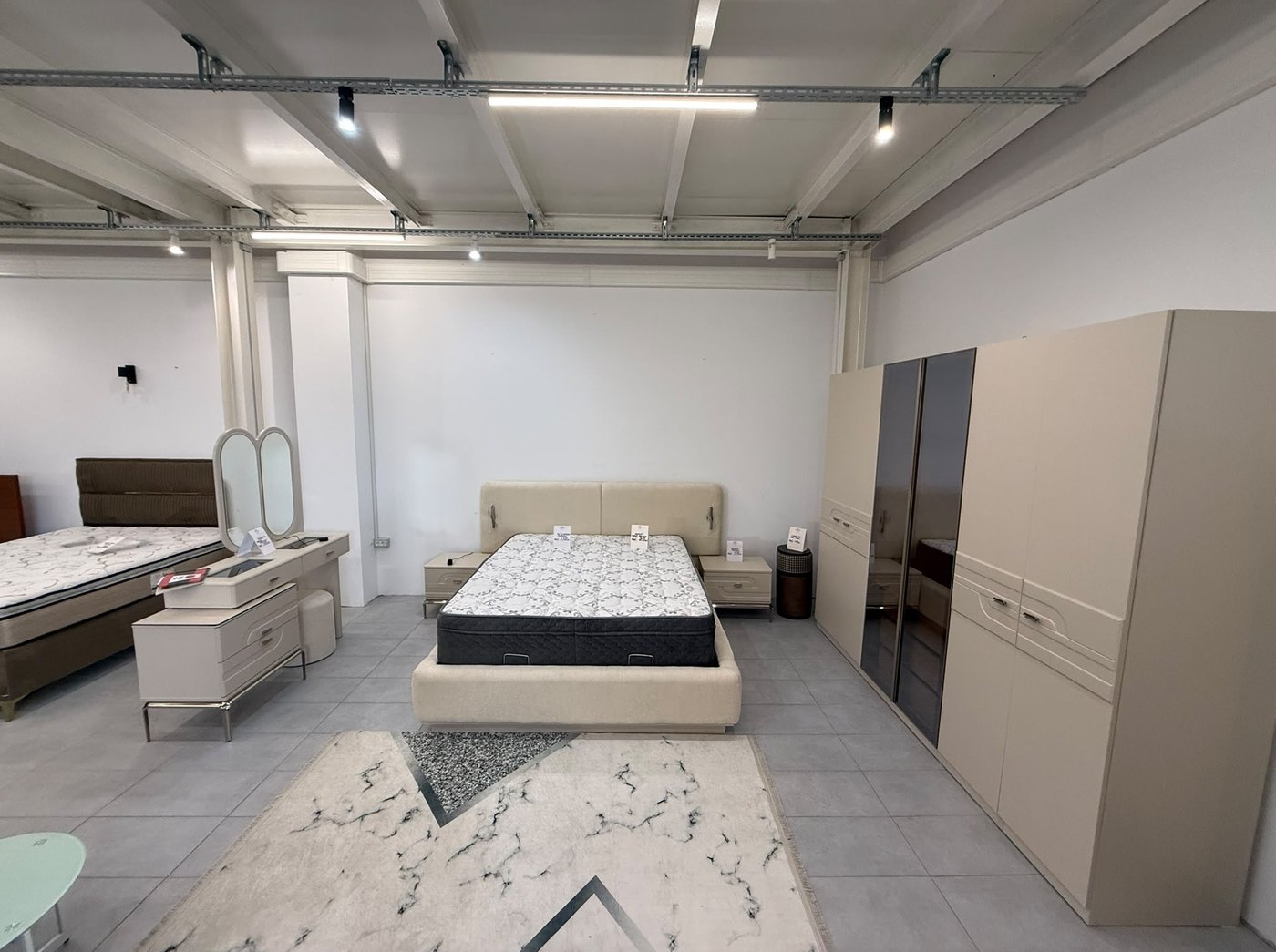 Dormitor in showroom cu tavan industrial, alte paturi in fundal si saltea goala
